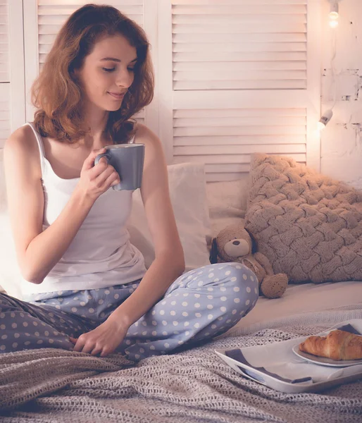 Красива жінка п'є каву, сидячи на ліжку вдома — стокове фото