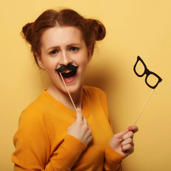 Jonge vrouw met nep-snorren en brillen over gele backgro — Stockfoto