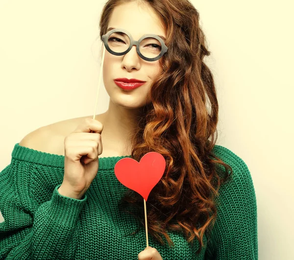 Jovencita juguetona sosteniendo unas gafas de fiesta . — Foto de Stock