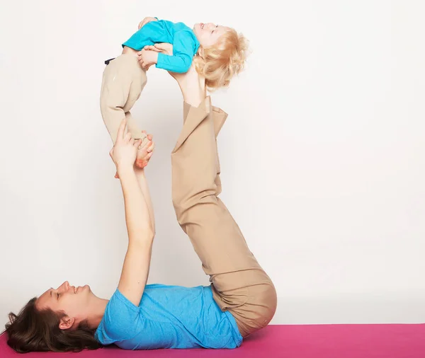 Esporte e conceito de pessoas: pai e seu filho fazendo exercício de ioga no estúdio fundo branco . — Fotografia de Stock