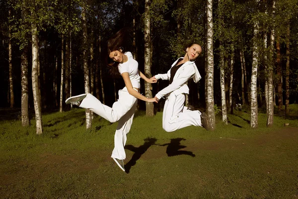 Twee jonge meisje sprong in park — Stockfoto