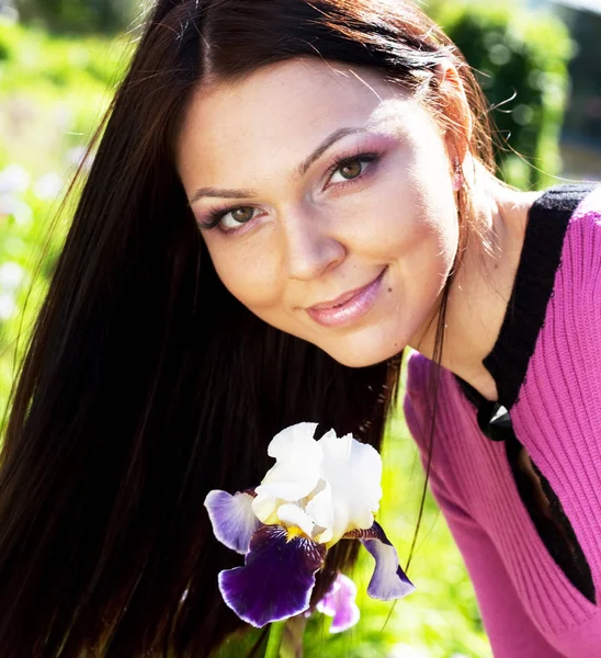 Woman smiling outdoors with some flowers — Stock Photo, Image