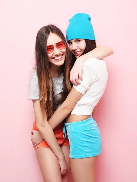 Glücklich lächelnd hübsche Teenager-Mädchen oder Freunde, die sich über rosa umarmen — Stockfoto