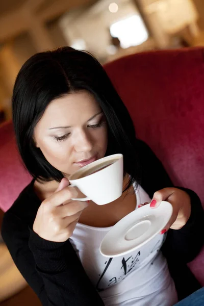 Jovem mulher sentada em um café bebendo café — Fotografia de Stock