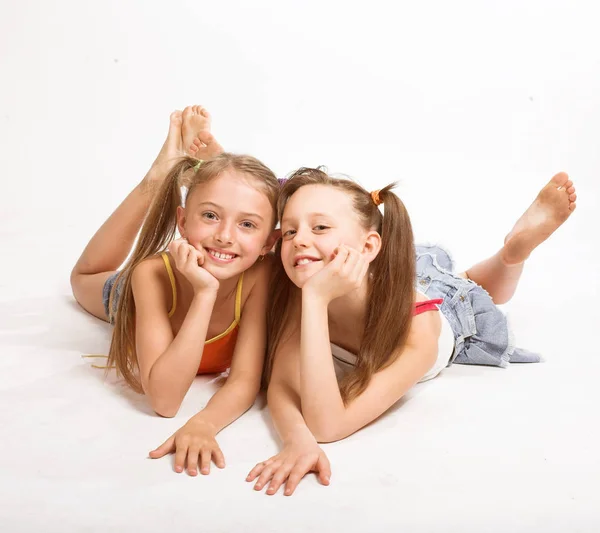 Duas meninas bonitas que colocam no branco — Fotografia de Stock