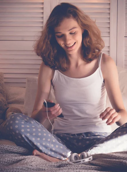 Молода жінка розслабляється в ліжку, вона слухає музику — стокове фото