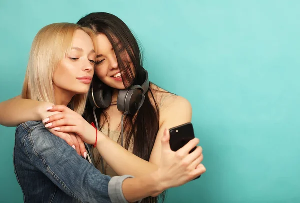 Duas meninas amigas em roupa hipster fazer selfie em um telefone . — Fotografia de Stock