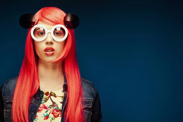 Fashion girl with pink hair and big sunglasses over blue  background — Stock Photo, Image