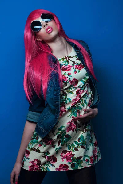 蓝色背景的粉色头发和大太阳镜的时装模特 — 图库照片