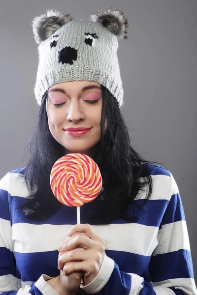 Mujer con sombrero mirando a la cámara y sosteniendo una lollipo — Foto de Stock