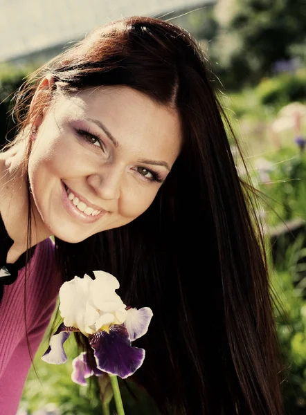 Woman smiling outdoors with some flowers — Stock Photo, Image