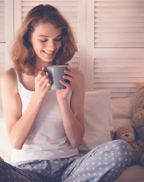 Mooie vrouw die thuis koffie drinkt zittend op bed — Stockfoto