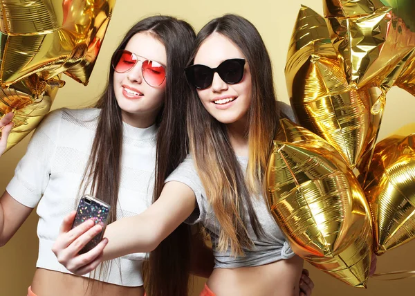 Two teenage girls friends with gold balloons  make selfie on a p — Stock Photo, Image