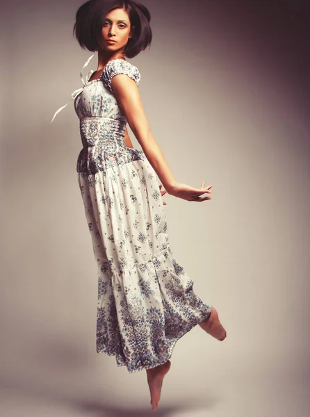 Joven mujer encantadora en vestido de gasa saltando sobre backgro gris — Foto de Stock