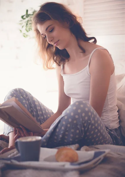 Meisje in bed lezen en koffie drinken — Stockfoto