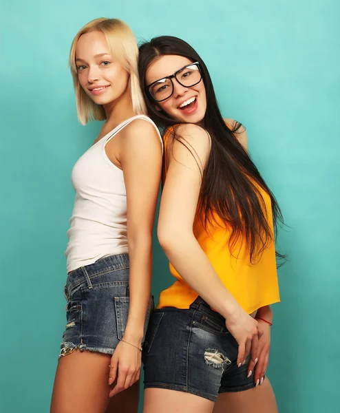 Two young girl friends standing together and having fun. Over bl — Stock Photo, Image