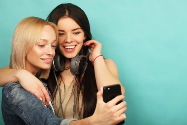 İki kız arkadaş hipster kıyafeti selfie olun bir telefonda.