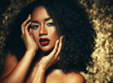 afro saçlı genç zarif Afrikalı-Amerikalı kadın. Glamour makyaj. Altın arka plan.