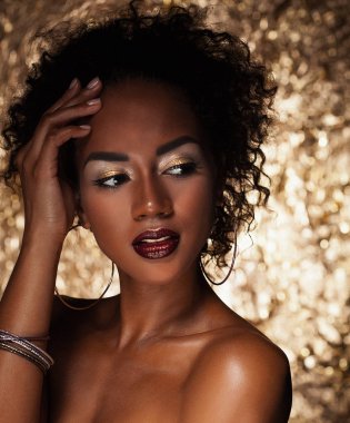 afro saçlı genç zarif Afrikalı-Amerikalı kadın. Glamour makyaj. Altın arka plan.