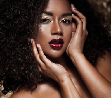 afro saçlı genç zarif Afrikalı-Amerikalı kadın. Glamour makyaj. Altın arka plan.