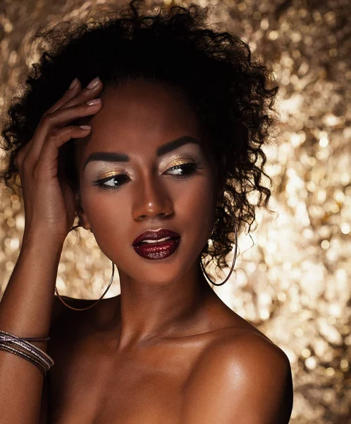 Joven elegante mujer afroamericana con pelo afro. Maquillaje de glamour. Fondo dorado . — Foto de Stock