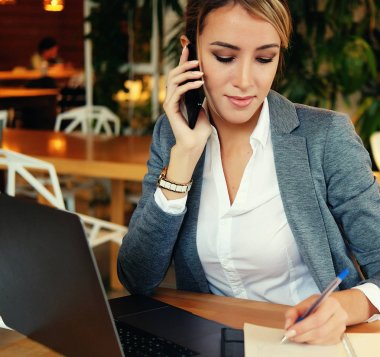 Cep telefonu ve dizüstü bilgisayar kullanan mutlu bir kadın.