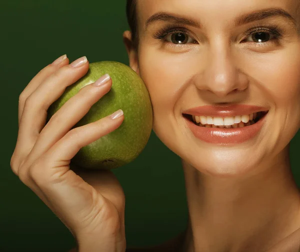 Head shot of woman holding green apple against green background — Stock Photo, Image