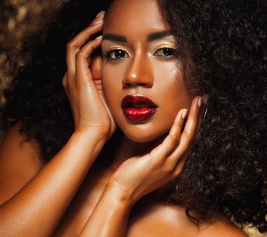 afro saçlı genç zarif Afrikalı-Amerikalı kadın. Glamour makyaj. Altın arka plan.