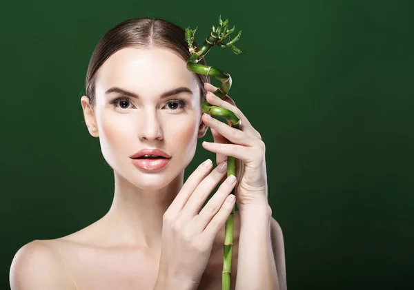 Mooie vrouw met bamboe geïsoleerd op groene achtergrond — Stockfoto