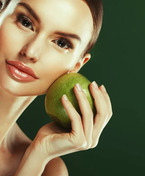 Mujer joven con manzana verde sobre fondo verde — Foto de Stock