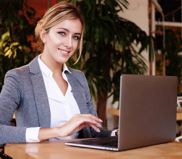 Trabajaba con una computadora portátil en la cafetería. Joven hermosa chica sitti — Foto de Stock