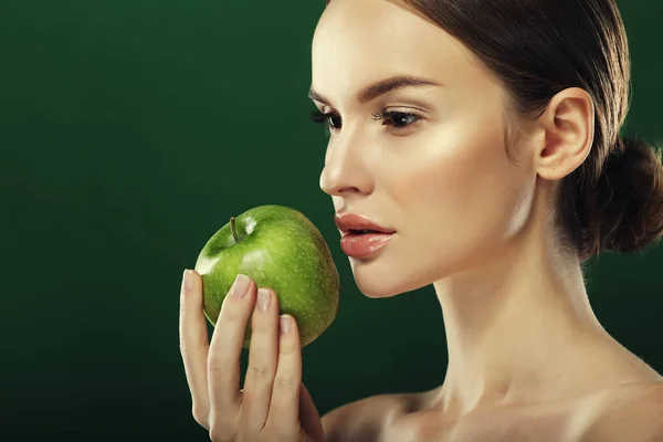 Head shot of woman holding green apple against green background — Stock Photo, Image
