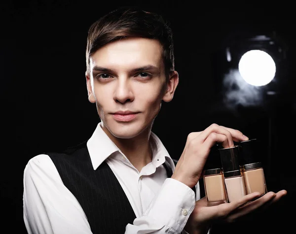 Молодой мужчина гример позирует с фундаментом для макияжа о — стоковое фото