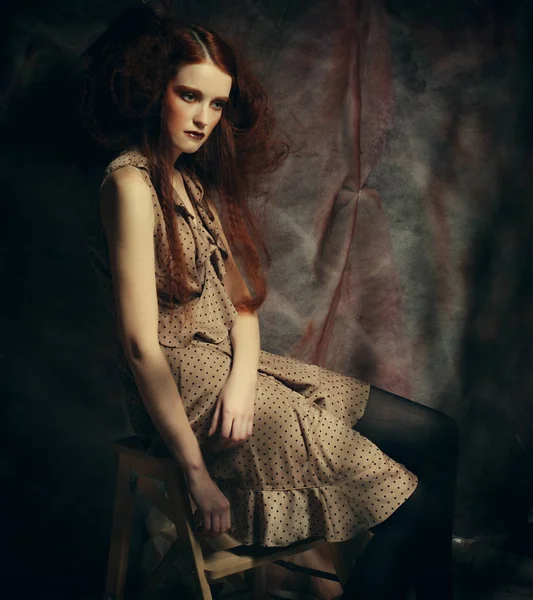 Modelo de moda joven con maquillaje creativo sentado en un taburete en — Foto de Stock