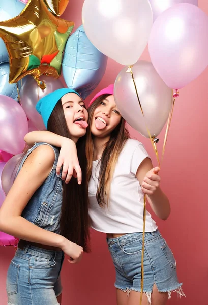 Dos chicas muy emocionales sostienen globos y posan contra pin —  Fotos de Stock