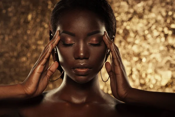 Gambar studio fashion dari model Amerika afrika yang luar biasa indah dengan mata tertutup di atas latar belakang emas — Stok Foto