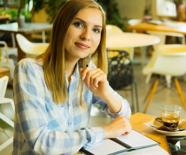 Zeki kadın fikirlerini yazıyor ve kafede kahve içiyor.