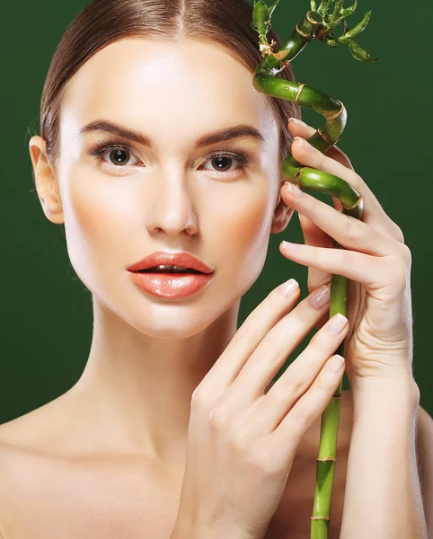 Junge schöne Frau mit Bambus auf grünem Hintergrund — Stockfoto