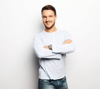 Akıllı, sıradan giyinmiş yakışıklı genç adam kameraya bakıyor.