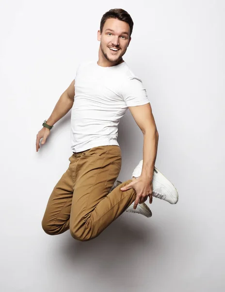 Sorridente uomo gioioso che salta su uno sfondo bianco . — Foto Stock