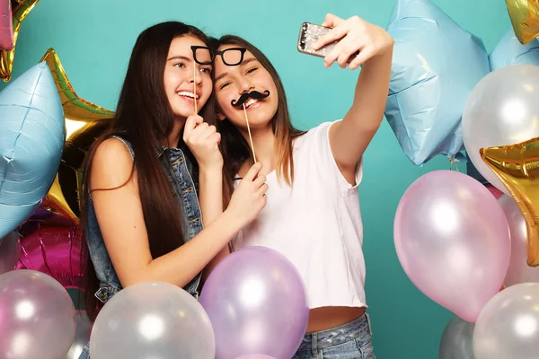 Zwei Freundinnen mit bunten Luftballons machen Selfie auf einem Foto — Stockfoto