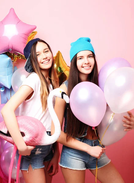 Δύο όμορφα συναισθηματικά κορίτσια κρατούν μπαλόνια και ποζάρουν ενάντια στην καρφίτσα — Φωτογραφία Αρχείου