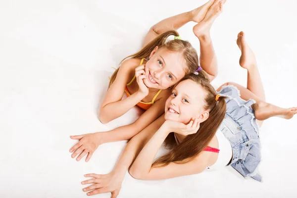 Duas meninas bonitas que colocam no branco — Fotografia de Stock