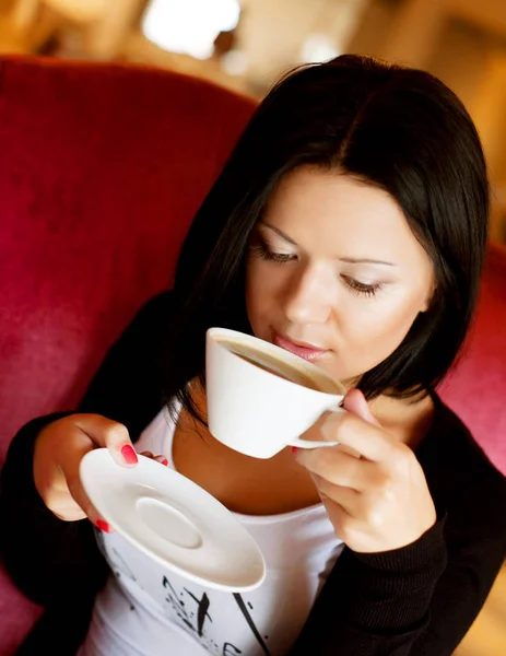 Jovem mulher sentada em um café bebendo café — Fotografia de Stock