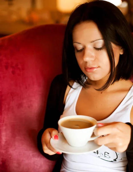 Jovem mulher sentada em um café bebendo café — Fotografia de Stock