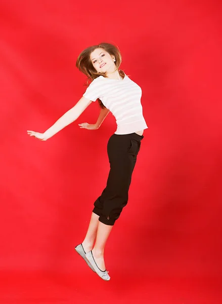 Chica saltando de alegría sobre rojo — Foto de Stock