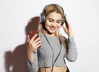 Kulaklıklı güzel sarışın kadın beyazdan müzik dinliyor.