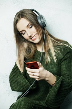 İnsanlar ve teknoloji kavramı - kulaklıklı mutlu kadın akıllı telefondan müzik dinliyor.