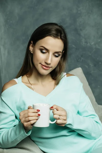 Прекрасно і мило. Красива молода жінка тримає чашку кави і сидить на стільці вдома. Концепція стилю . — стокове фото