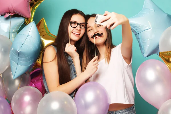 Dwie dziewczyny z kolorowymi balonami robią selfie na pniu — Zdjęcie stockowe